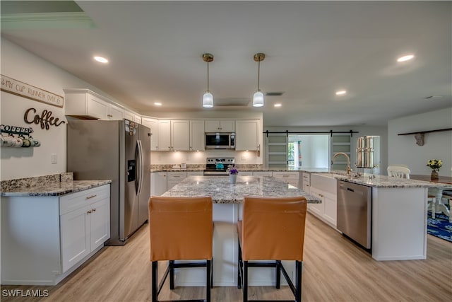 kitchen with white cabinetry, kitchen peninsula, a barn door, light hardwood / wood-style flooring, and stainless steel appliances