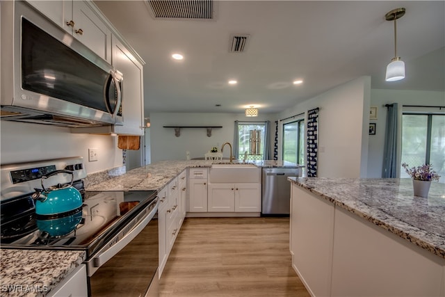 kitchen with hanging light fixtures, light hardwood / wood-style flooring, white cabinetry, stainless steel appliances, and light stone countertops