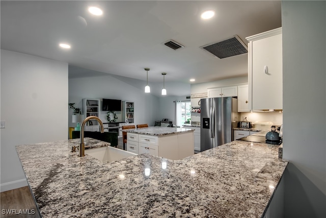 kitchen with a center island, sink, stainless steel refrigerator with ice dispenser, white cabinetry, and light stone countertops