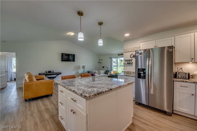 kitchen with white cabinets, vaulted ceiling, and stainless steel fridge