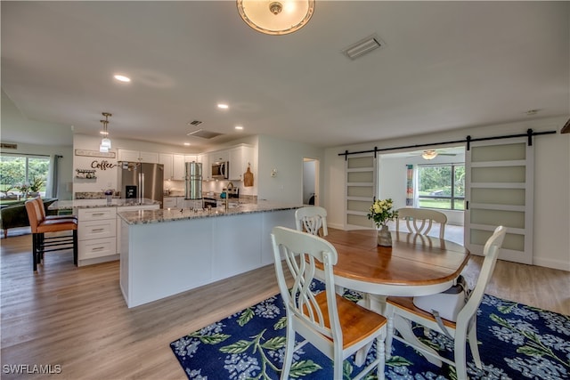 dining space featuring a barn door and light wood-type flooring