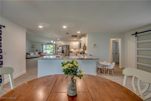 dining room with sink, light wood-type flooring, and a barn door