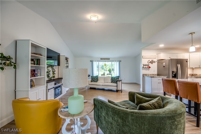 living room featuring lofted ceiling and light hardwood / wood-style flooring