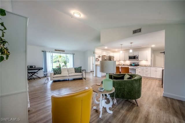 living room featuring vaulted ceiling and light hardwood / wood-style floors