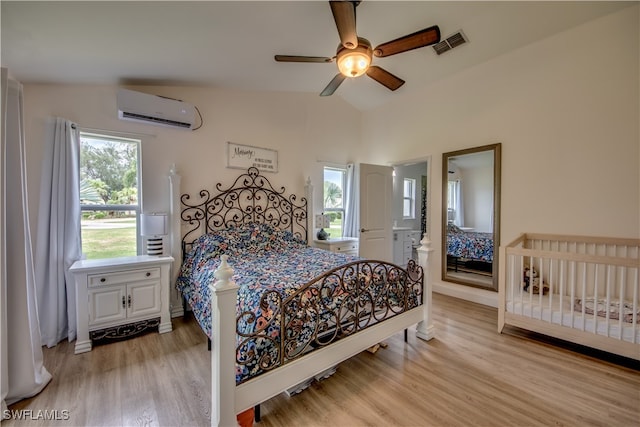 bedroom featuring vaulted ceiling, light hardwood / wood-style floors, ceiling fan, and a wall mounted air conditioner