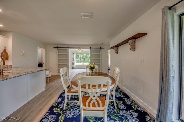 dining room featuring sink, light hardwood / wood-style flooring, and a barn door