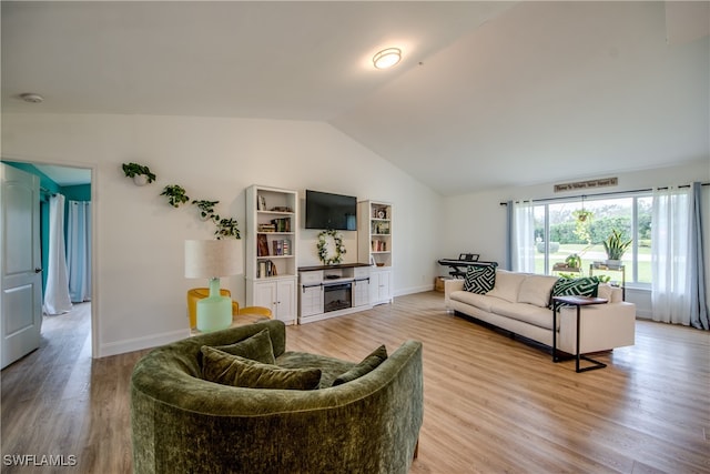 living room featuring light wood-type flooring, lofted ceiling, and a fireplace