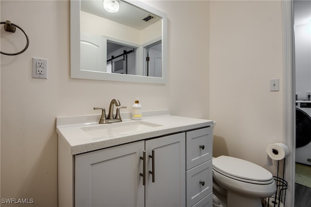 bathroom with washer / clothes dryer, vanity, and toilet