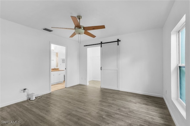 interior space featuring a barn door, hardwood / wood-style flooring, ceiling fan, and a healthy amount of sunlight