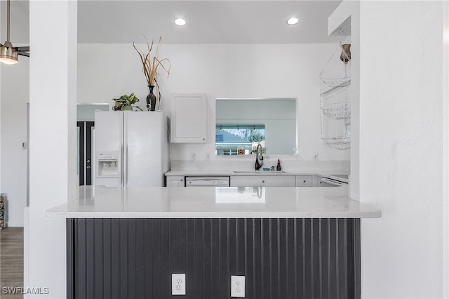 kitchen with white appliances, sink, kitchen peninsula, white cabinetry, and wood-type flooring