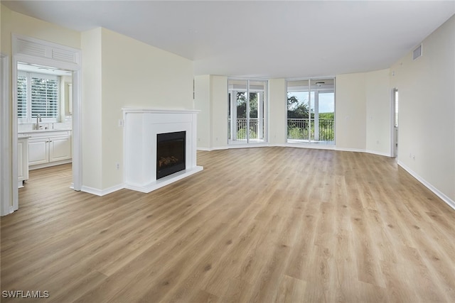 unfurnished living room featuring sink and light hardwood / wood-style flooring