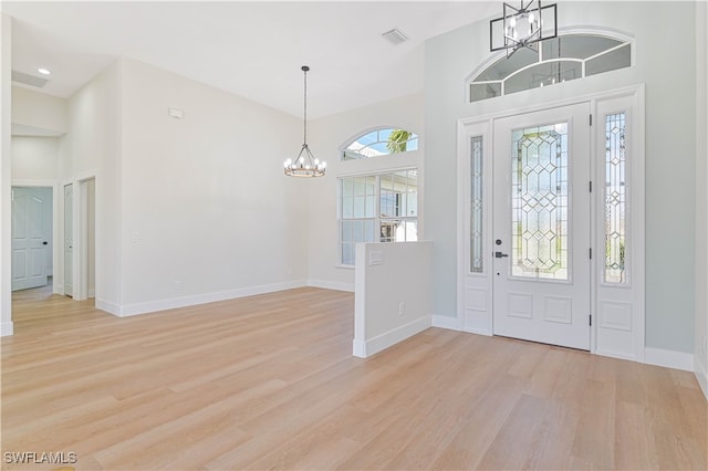 foyer featuring a high ceiling, a chandelier, and light wood-type flooring