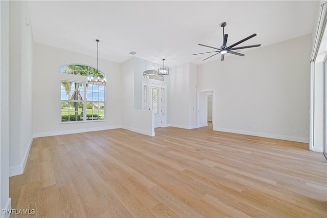 unfurnished living room featuring ceiling fan with notable chandelier and light hardwood / wood-style flooring