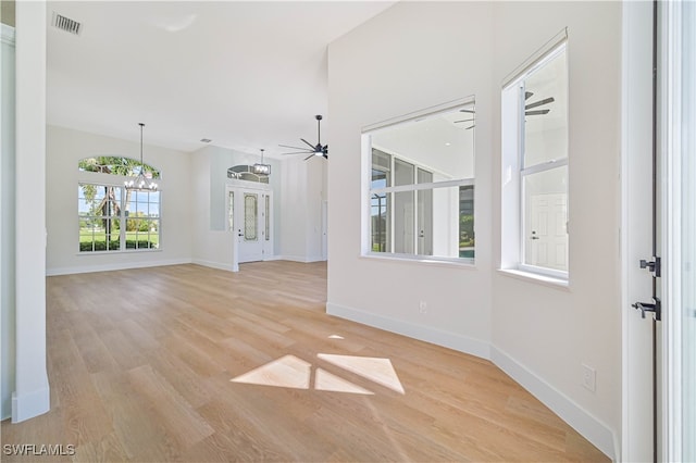 unfurnished room featuring a notable chandelier and light wood-type flooring