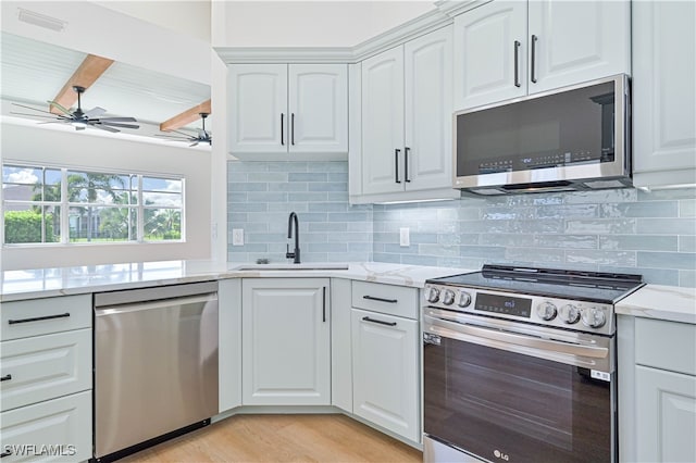 kitchen with ceiling fan, white cabinets, light stone counters, appliances with stainless steel finishes, and light hardwood / wood-style floors