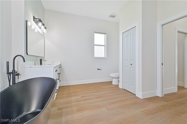 bathroom with wood-type flooring, vanity, toilet, and a tub