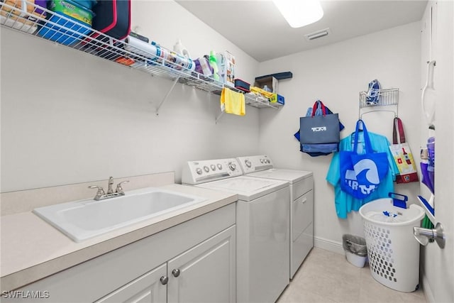 clothes washing area featuring sink, light tile patterned floors, and washer and dryer