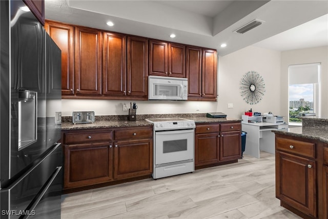 kitchen featuring light wood-type flooring, white appliances, and dark stone countertops