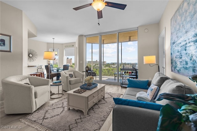 living room featuring ceiling fan, floor to ceiling windows, and light wood-type flooring