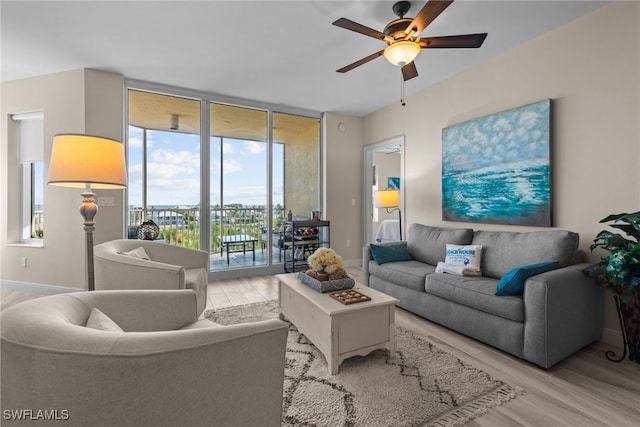 living room with floor to ceiling windows, ceiling fan, and light wood-type flooring