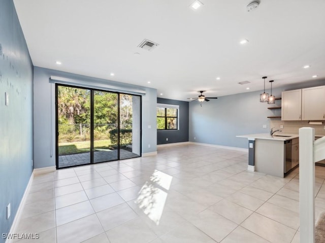 unfurnished living room with light tile patterned flooring, sink, and ceiling fan