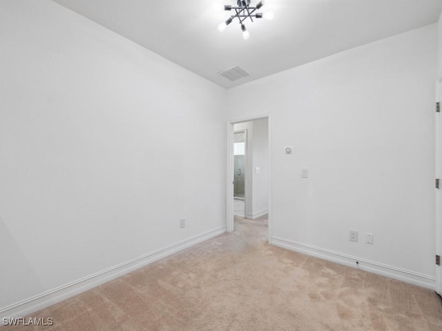 carpeted empty room featuring an inviting chandelier