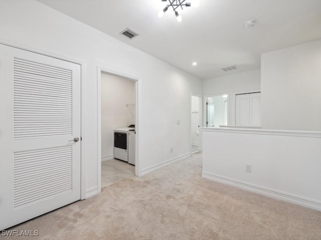 spare room with light colored carpet and washer and dryer