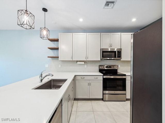 kitchen with sink, light tile patterned floors, appliances with stainless steel finishes, hanging light fixtures, and white cabinets