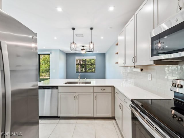 kitchen featuring pendant lighting, sink, backsplash, kitchen peninsula, and stainless steel appliances