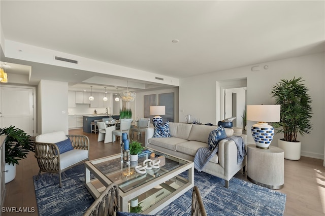 living area featuring a tray ceiling, wood finished floors, and visible vents