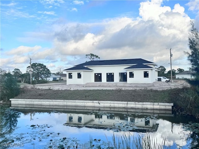 rear view of property featuring a water view and stucco siding