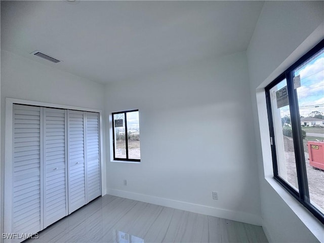 unfurnished bedroom with a closet and multiple windows