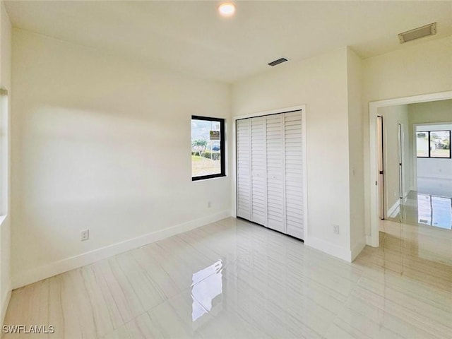 unfurnished bedroom with baseboards, multiple windows, and visible vents