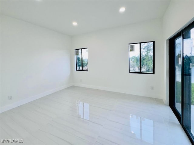 spare room with recessed lighting, plenty of natural light, and baseboards