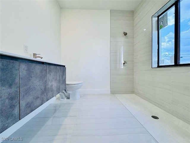 full bathroom with tile patterned flooring, a tile shower, toilet, and baseboards