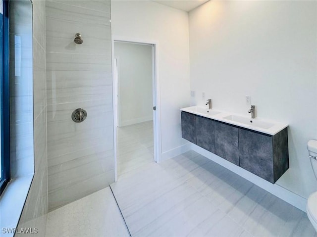 full bathroom featuring toilet, baseboards, walk in shower, and a sink