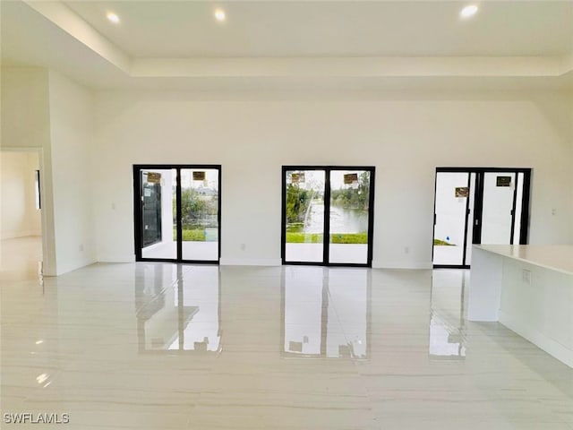 empty room with a high ceiling, plenty of natural light, recessed lighting, and baseboards