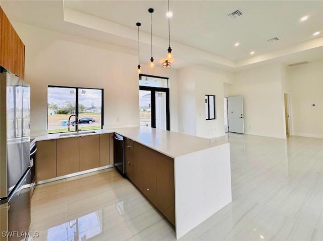 kitchen with a tray ceiling, visible vents, freestanding refrigerator, a sink, and modern cabinets