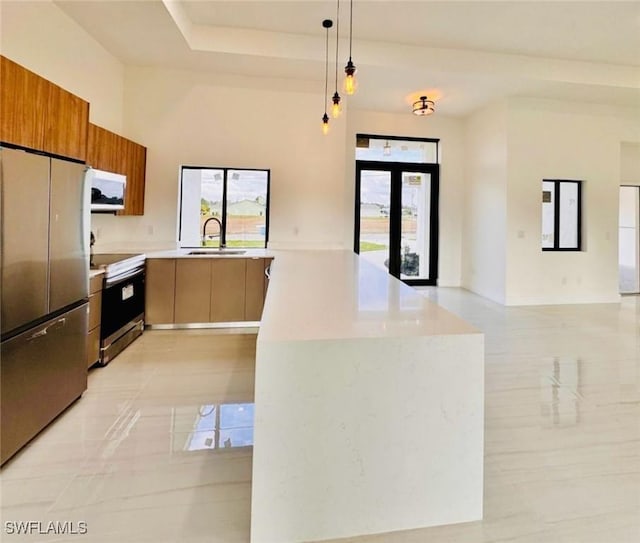 kitchen with decorative light fixtures, appliances with stainless steel finishes, a sink, modern cabinets, and a peninsula