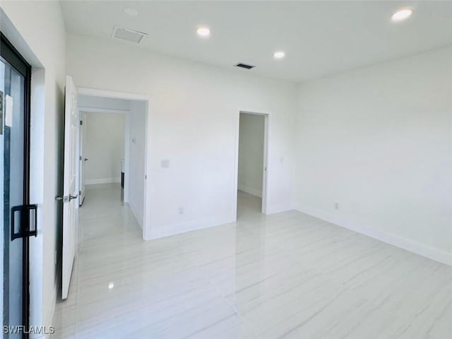 unfurnished room featuring baseboards, visible vents, and recessed lighting