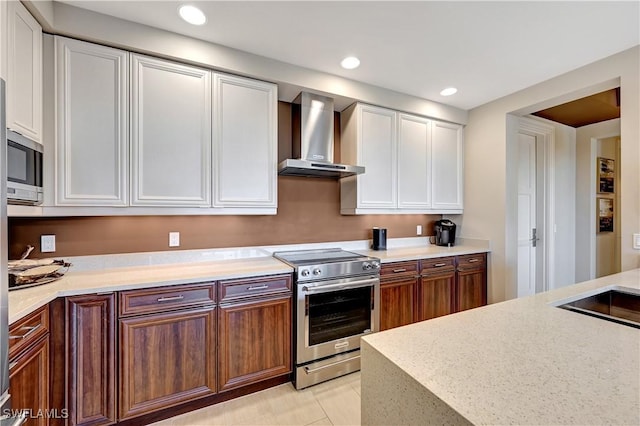 kitchen featuring white cabinets, light tile patterned floors, wall chimney exhaust hood, and appliances with stainless steel finishes