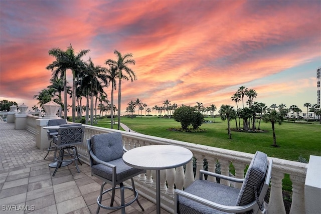 patio terrace at dusk with an outdoor kitchen and a lawn