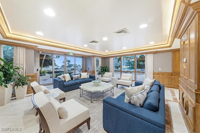 living room featuring ornamental molding, a healthy amount of sunlight, and a raised ceiling