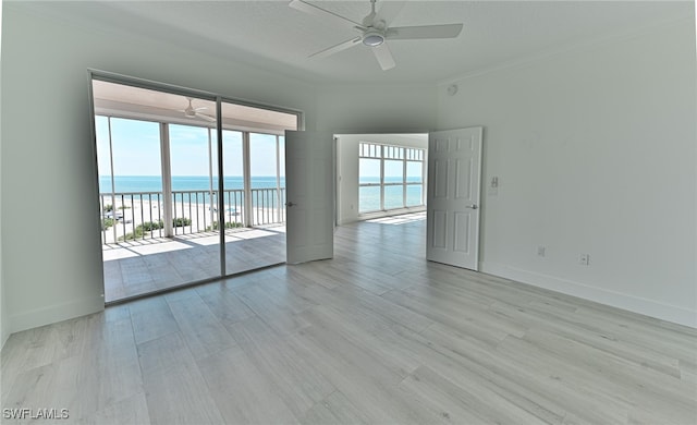 spare room featuring light hardwood / wood-style floors, a water view, ceiling fan, and crown molding