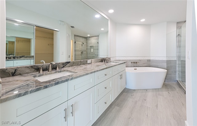 bathroom with independent shower and bath, vanity, and tile walls