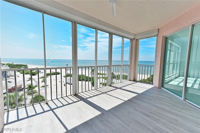 unfurnished sunroom with a beach view and a water view