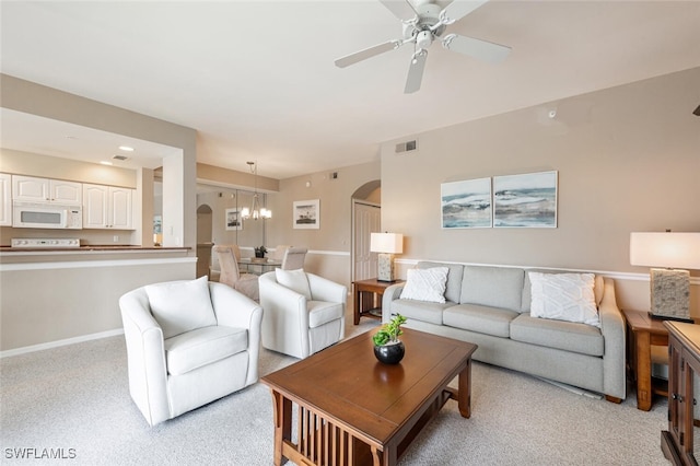 living room featuring ceiling fan with notable chandelier and light colored carpet