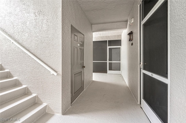 corridor featuring a textured ceiling and carpet flooring