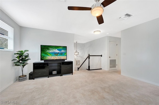 living area featuring ceiling fan, carpet flooring, visible vents, and baseboards