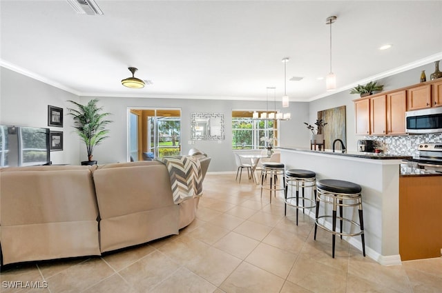 living room featuring crown molding, visible vents, light tile patterned flooring, a chandelier, and baseboards